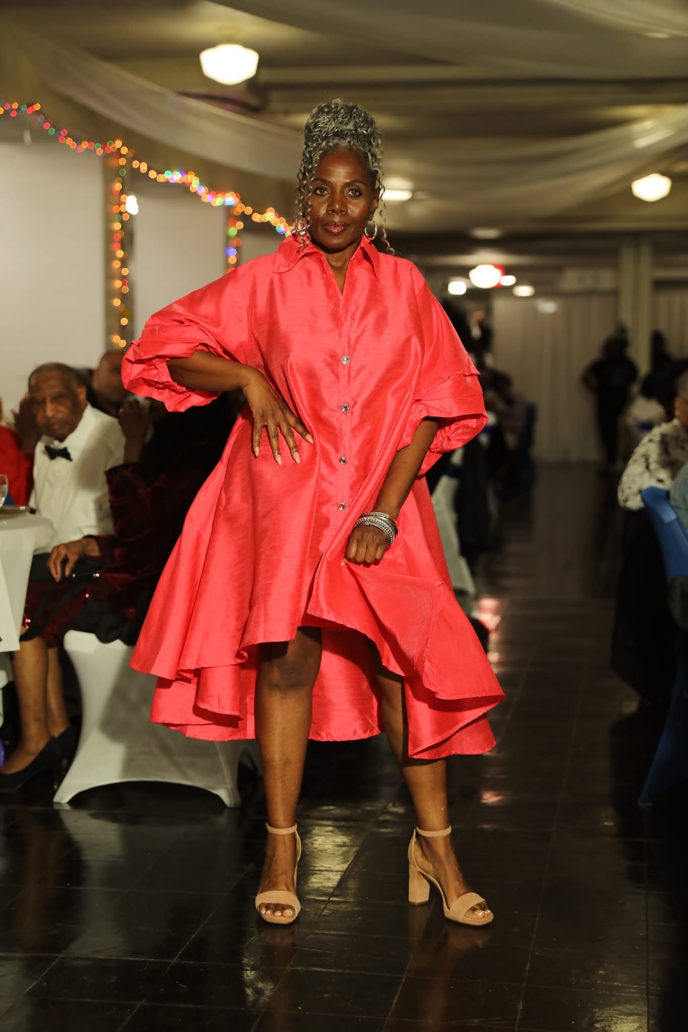 Woman in a bright pink dress posing on a stage with a blurred background