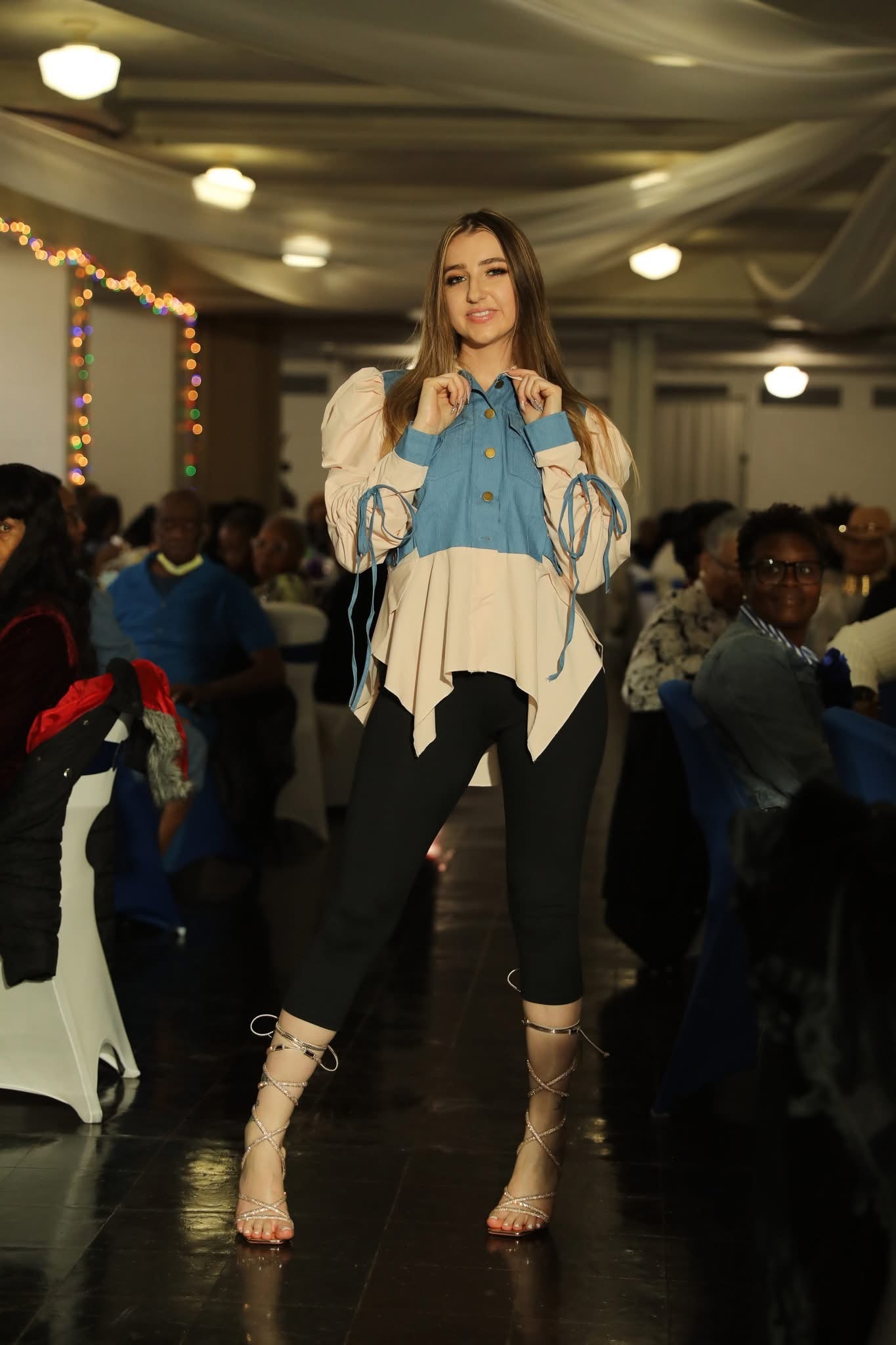 Model walking on a runway wearing a stylish outfit with a blue and white top.