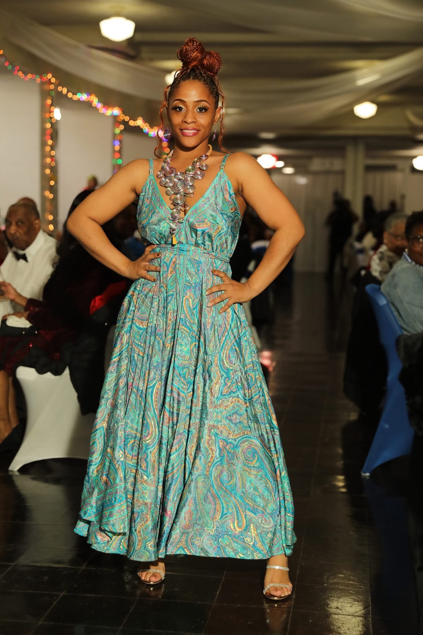 Woman in a patterned dress posing in an indoor setting with decorations.